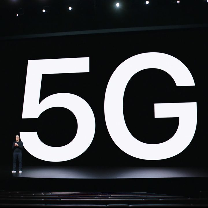 Apple CEO Tim Cook in front of a huge projection of the term 5G.