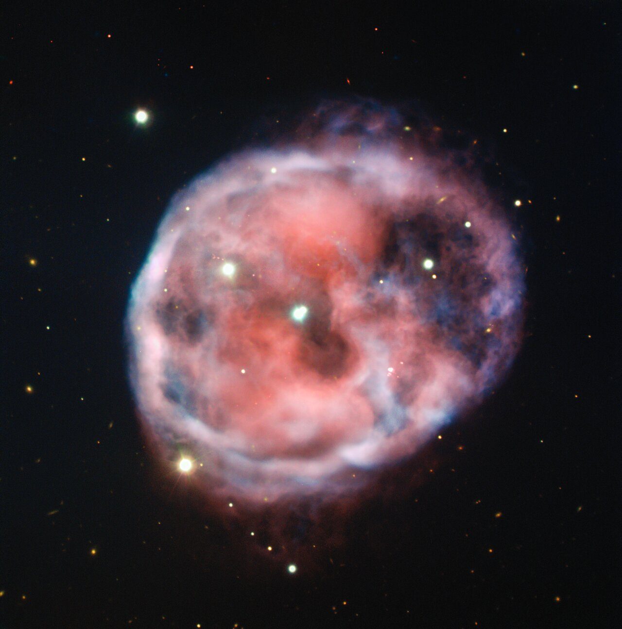 Captured in astounding detail by ESO’s Very Large Telescope (VLT), the eerie Skull Nebula is showcased in this new image in beautiful pink and red tones. This planetary nebula, also known as NGC 246, is the first known to be associated with a pair of closely bound stars orbited by a third outer star.