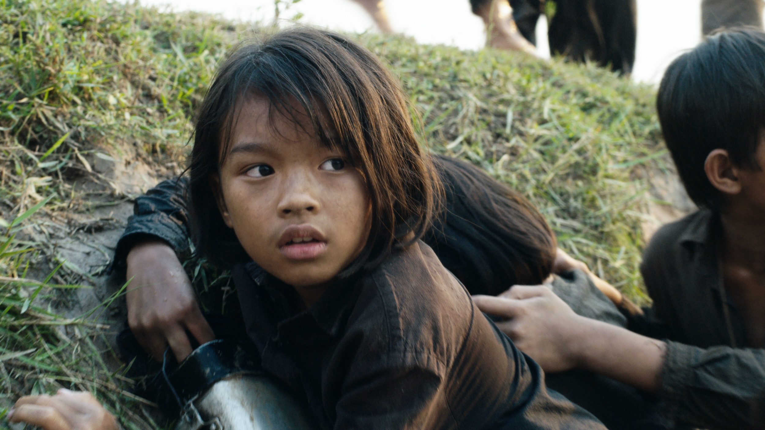 A child on the grass in First They Killed My Father.