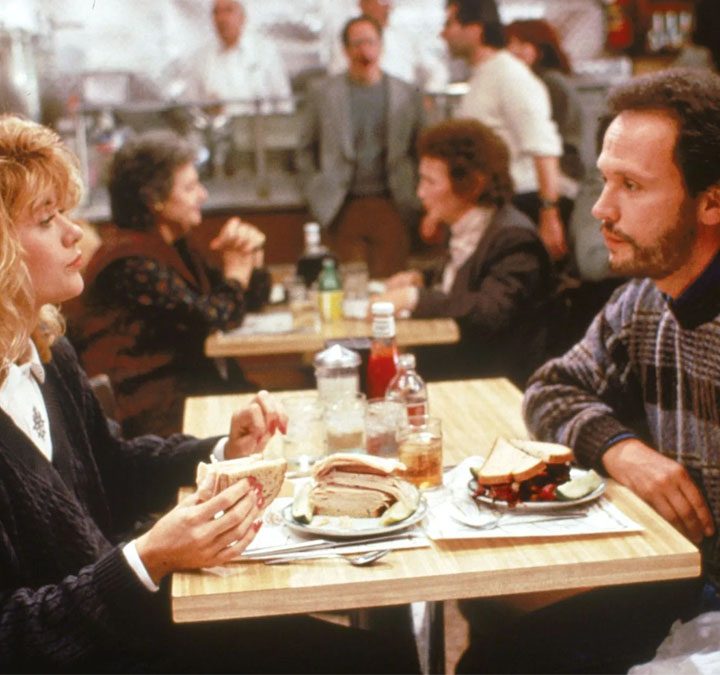 Meg Ryan and Billy Crystal as Sally and Harry sitting in a diner from the rom com When Harry Met Sally.