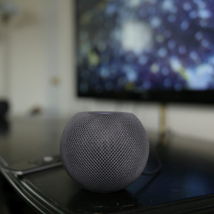 An Apple HomePod Mini sits on top of entertainment center.