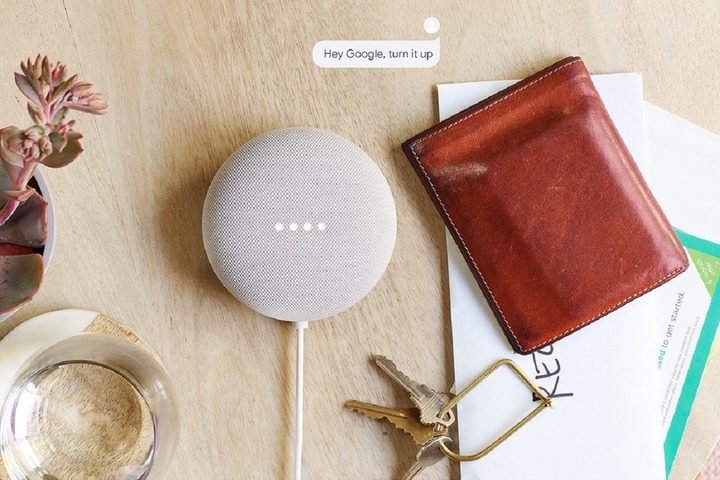Google's Nest Mini, white, on table with other personal belongings.