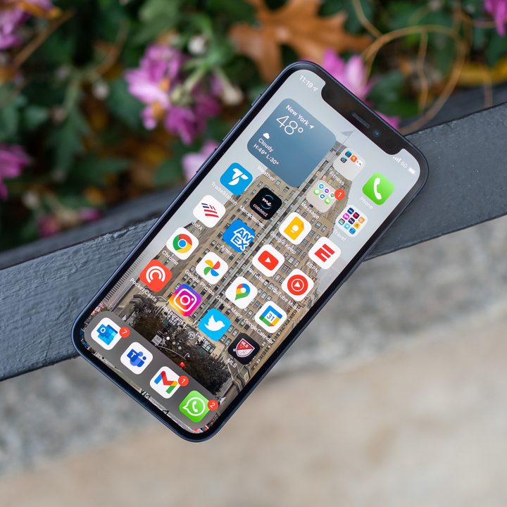 An iPhone 12 Mini rests on a rail with the screen activated.
