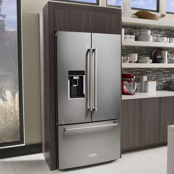 Kitchenaid fridge in kitchen while a woman cooks at the counter.
