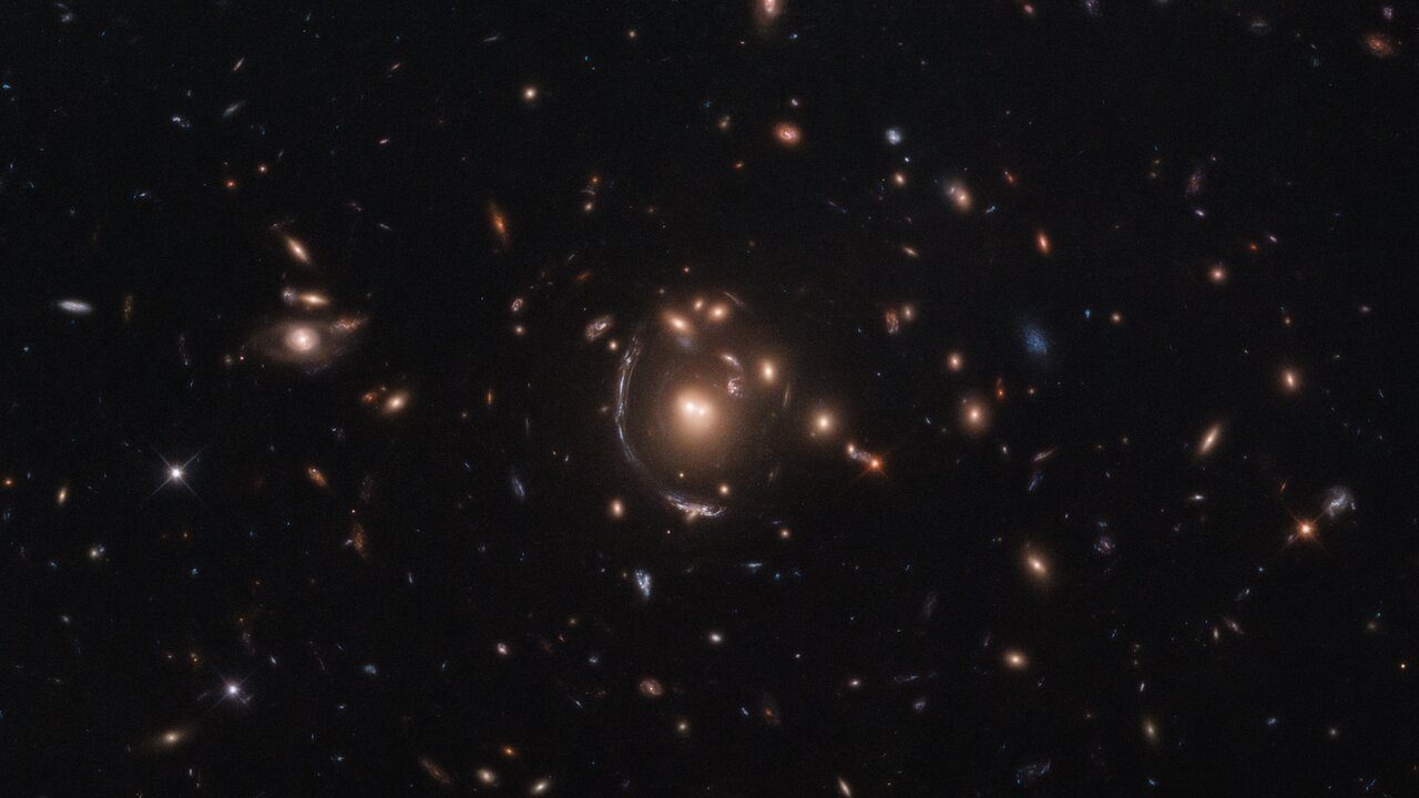 This NASA/ESA Hubble Space Telescope image features the galaxy LRG-3-817, also known as SDSS J090122.37+181432.3. The galaxy, its image distorted by the effects of gravitational lensing, appears as a long arc to the left of the central galaxy cluster.