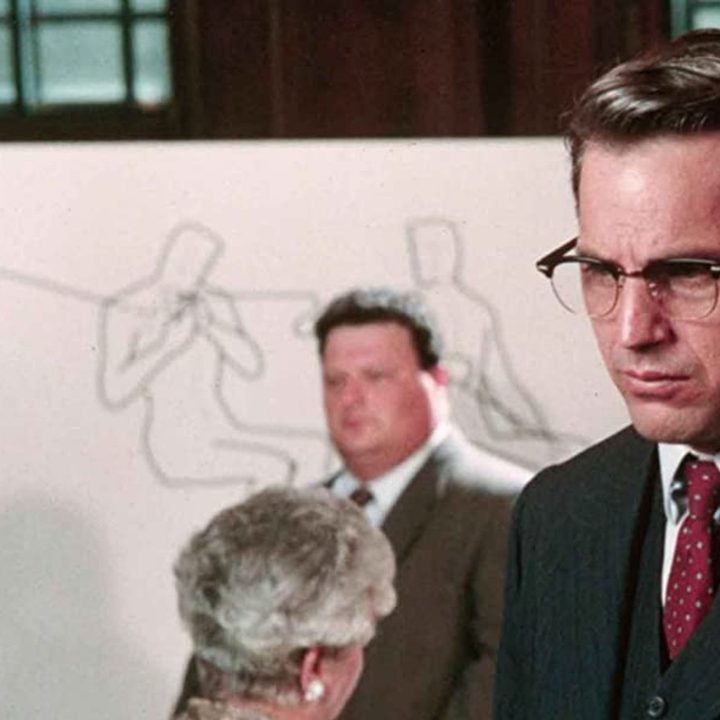 Kevin Costner stands in a courtroom in JFK.