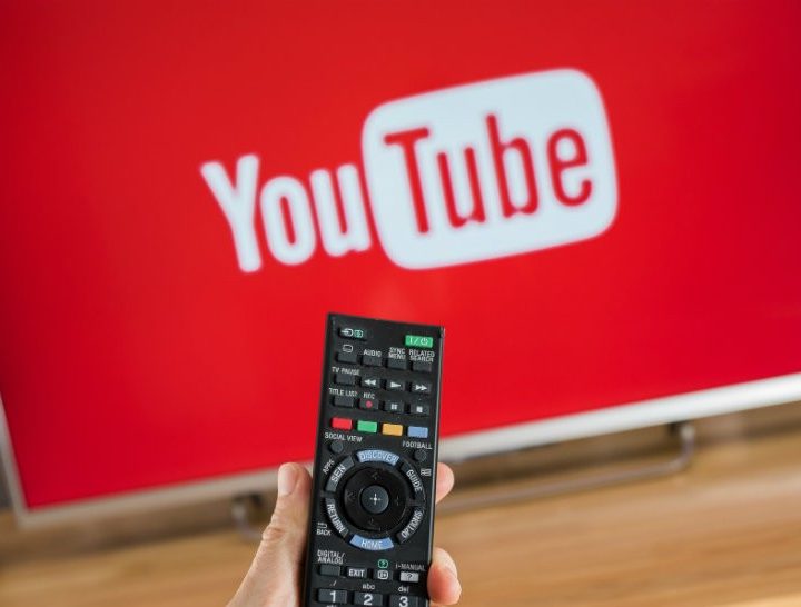 A person pointing a remote towards a TV with YouTube running.