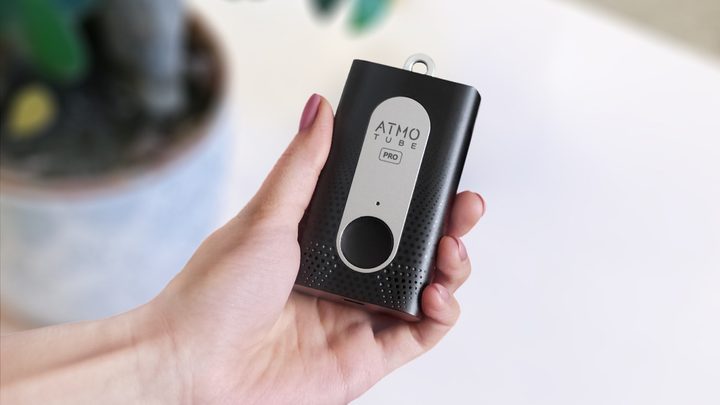 Hand holding the Atmotube Pro portable air quality monitor