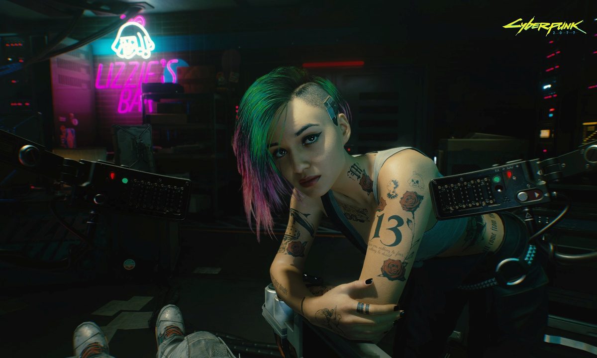 Judy leans over a table in Cyberpunk 2077.