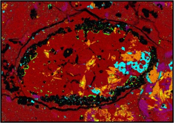SwRI scientists studied the composition of a small shard of a meteoroid to determine that it likely originated from a previously unknown parent asteroid. This false-color micrograph of the meteoroid sample shows the unexpected amphibole crystals identified in orange.