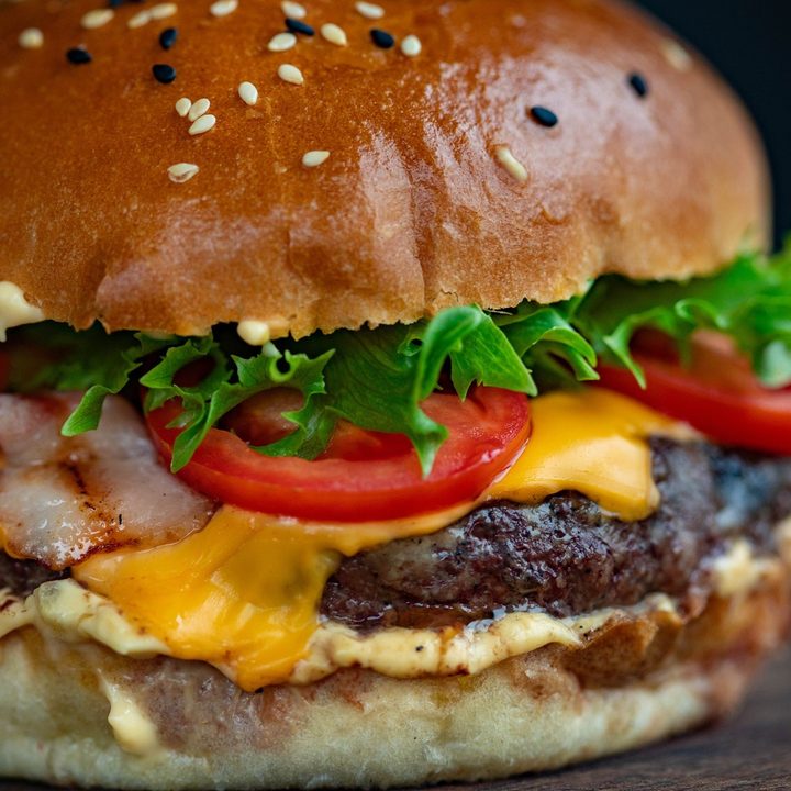 Close up of a cheeseburger with lettuce and tomato.