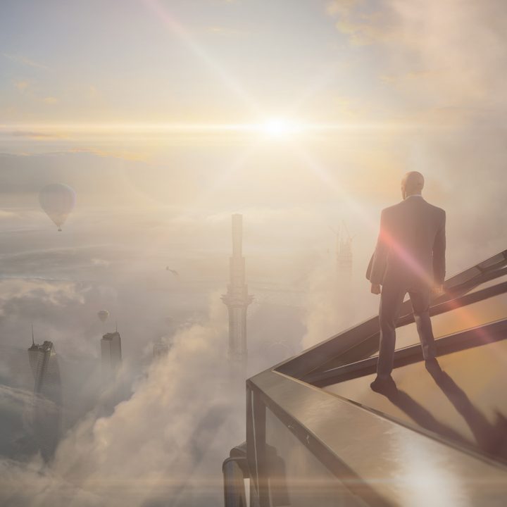 Agent 47 stands on top of a Dubai skyscraper in Hitman 3.