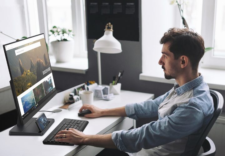 Man sitting at a desk using his desktop PC and smartphone.