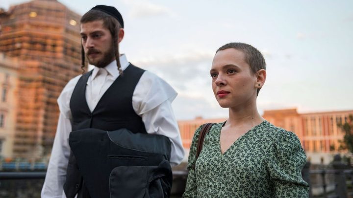 A man stands next to a young girl in Unorthodox.