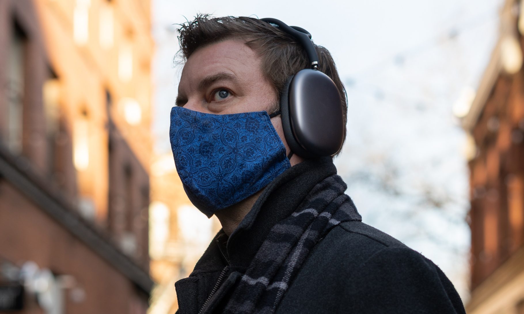 A man wears Apple AirPods Max headphones on a city street.