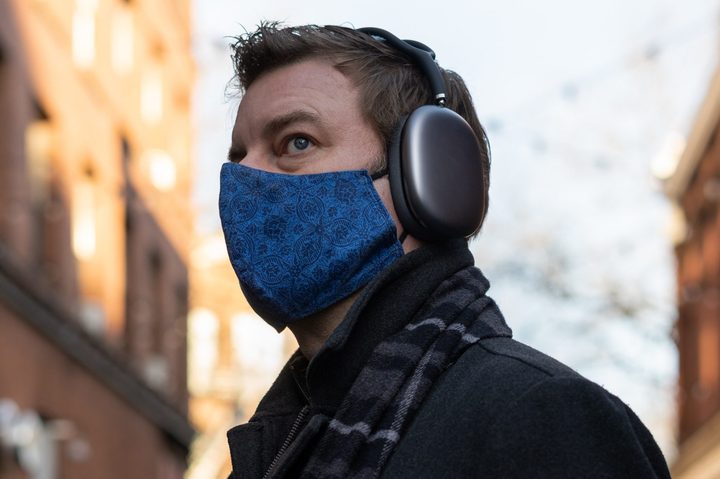 A man wears Apple AirPods Max headphones on a city street.