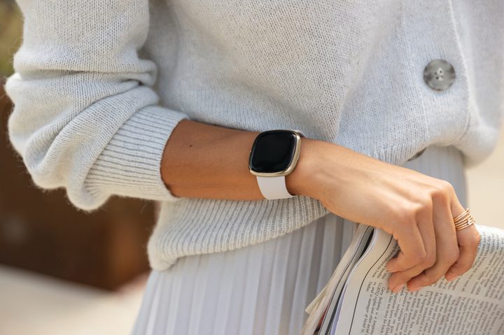 Close up shot of a woman wearing the Fitbit Sense on her wrist