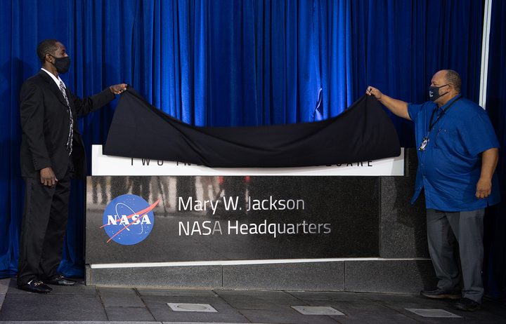 Bryan Jackson, grandson of Mary W. Jackson, left, and Raymond Lewis, son-in-law of Mary W. Jackson, right, unveil the Mary W. Jackson NASA Headquarters sign during a ceremony officially naming the building, Friday, Feb. 26, 2021, at NASA Headquarters in Washington, DC. Mary W. Jackson, the first African American female engineer at NASA, began her career with the agency in the segregated West Area Computing Unit of NASA&rsquo;s Langley Research Center in Hampton, Virginia. The mathematician and aerospace engineer went on to lead programs influencing the hiring and promotion of women in NASA's science, technology, engineering, and mathematics careers. In 2019, she posthumously received the Congressional Gold Medal. 