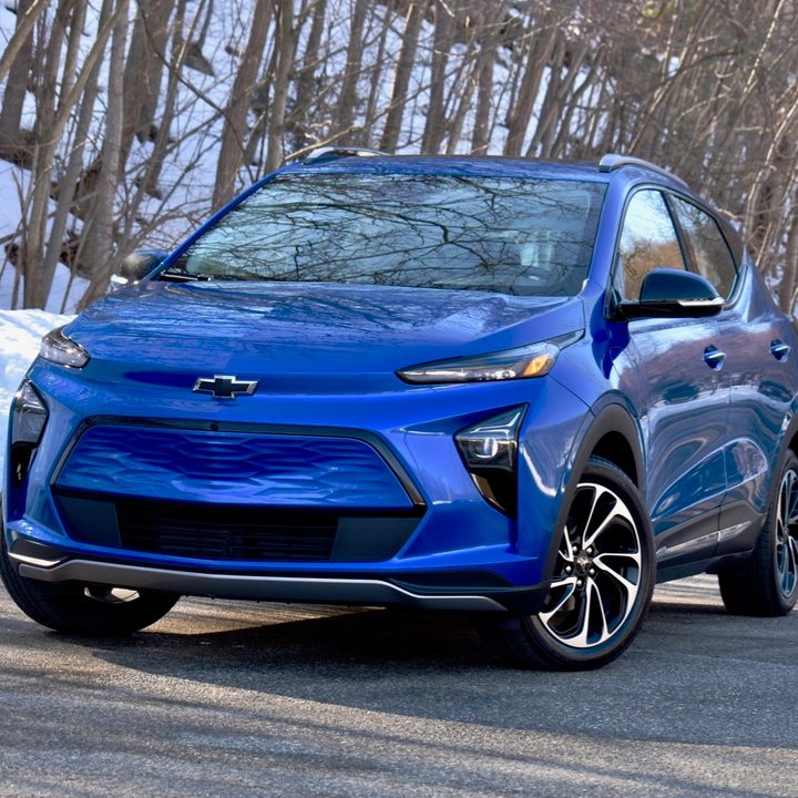 A blue Chevy Bolt against a snowy backdrop.