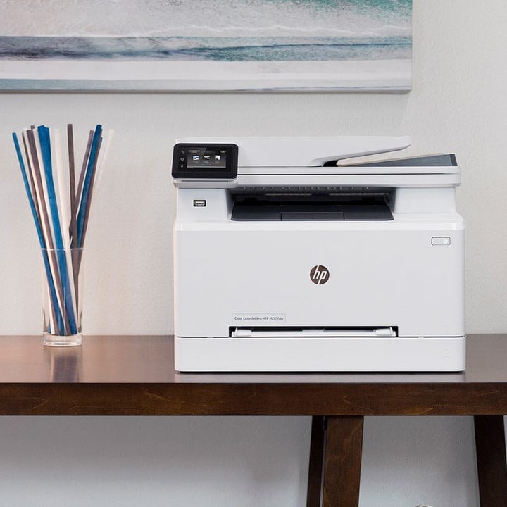 A printer sitting on a desk by a window.