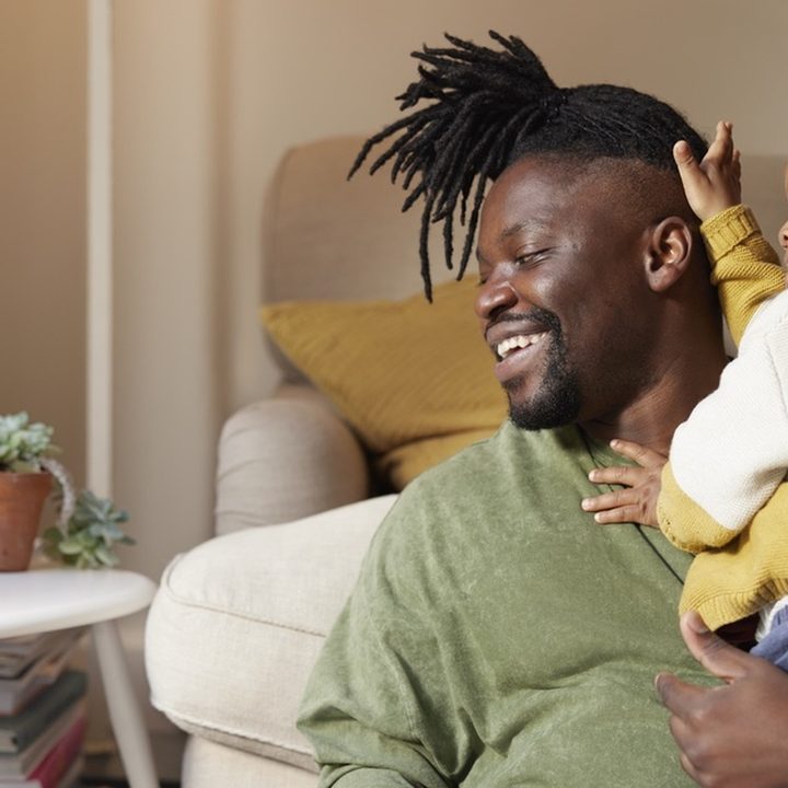 Man holding child and looking at a Nest Hub device.