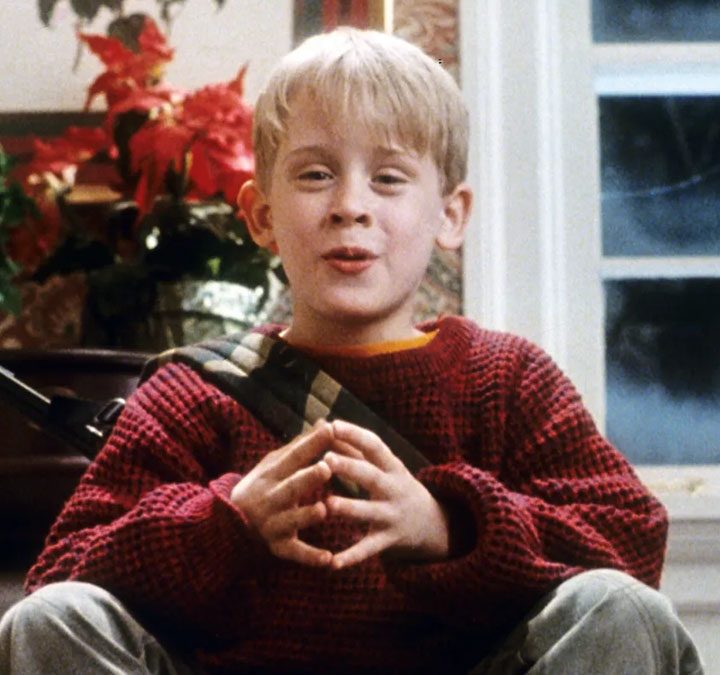A young boy sits on steps with a gun.