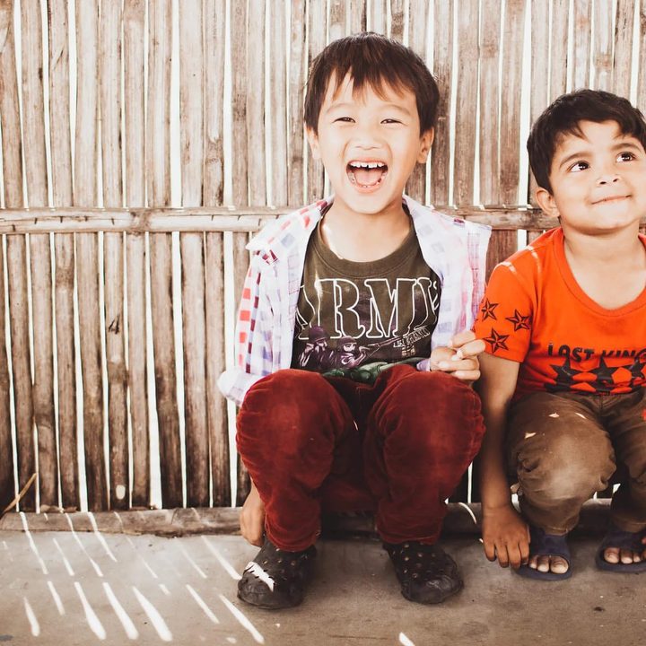 Kids sitting by a fence.