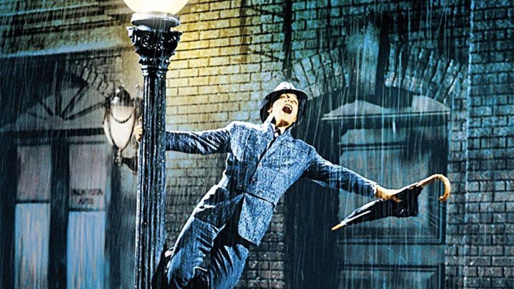 Gene Kelly as Don Lockwood singing under the rain while holding a lamp post in Singin' in the Rain (1952)