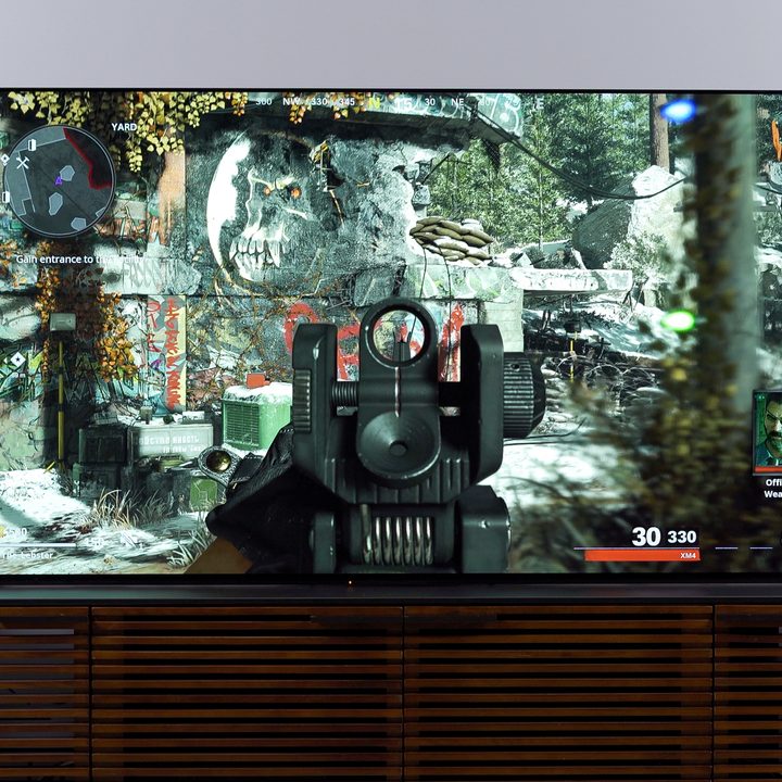 Sony Bravia XR A90J 4K OLED TV with a first-person shooter video game on the display next to a PlayStation 5.