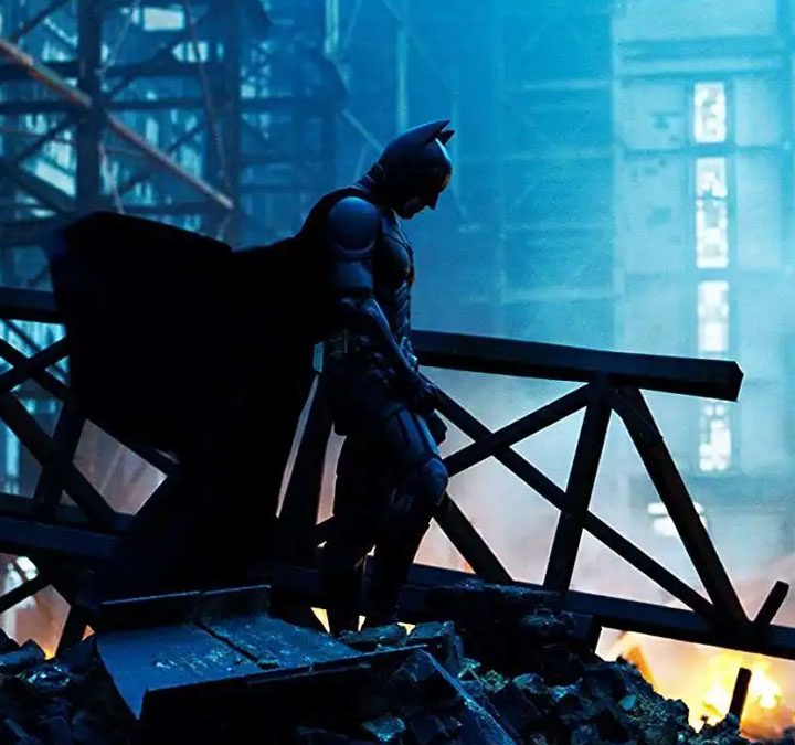Batman (Christian Bale) standing amid wreckage in The Dark Knight.