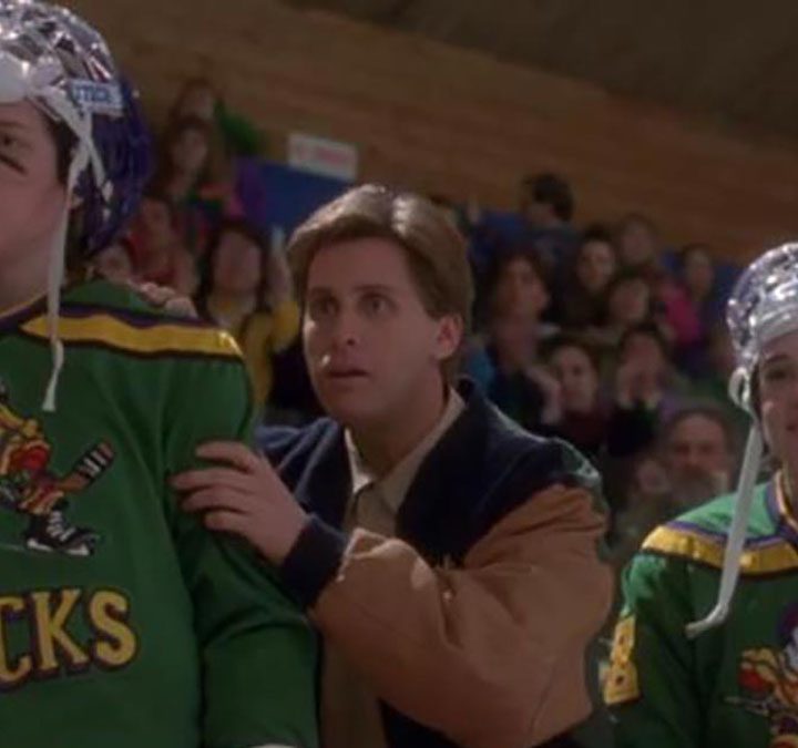A coach stands next to his players on the sideline in The Mighty Ducks.