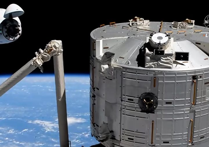 The SpaceX Crew Dragon approaches its space station docking port with the Kibo laboratory module in the foreground.