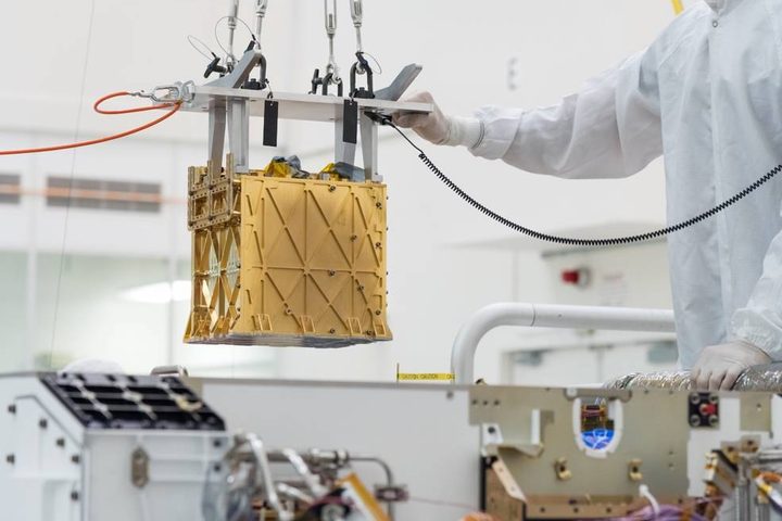 Technicians at NASA's Jet Propulsion Laboratory lower the Mars Oxygen In-Situ Resource Utilization Experiment (MOXIE) instrument into the belly of the Perseverance rover.