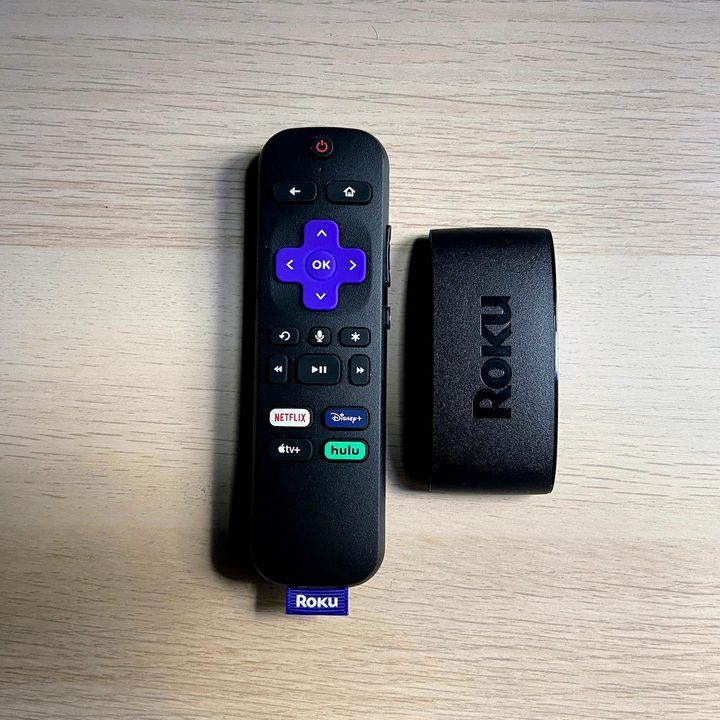 The Roku Express 4K Plus with remote on a wooden surface.