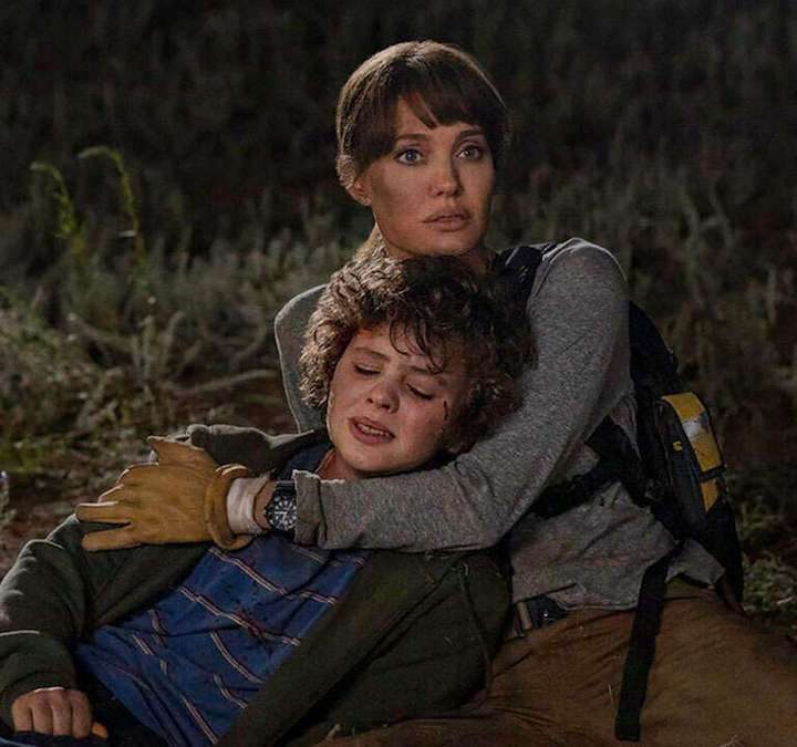 Angelina Jolie holds onto a kid in Those Who Wish Me Dead