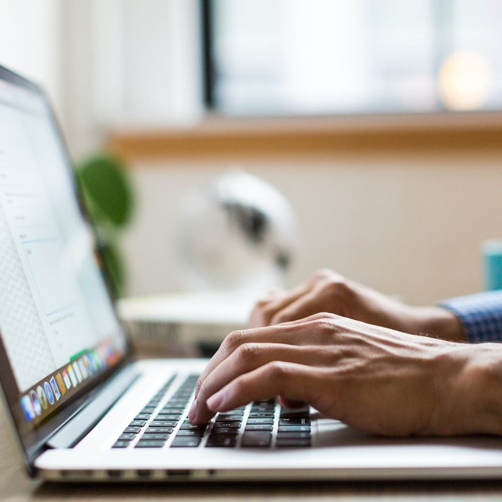 A man's hands typing on a laptop.