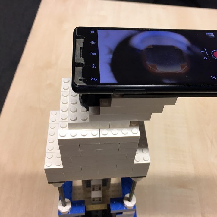 A mobile phone mounted on the top of a Lego microscope, serving as a lens.