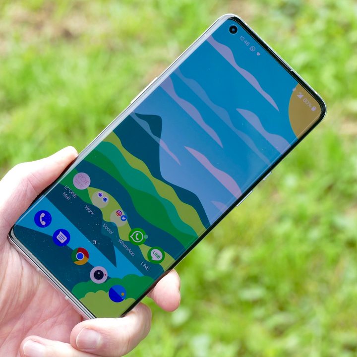 OnePlus 9 Pro held in hand, showing screen.