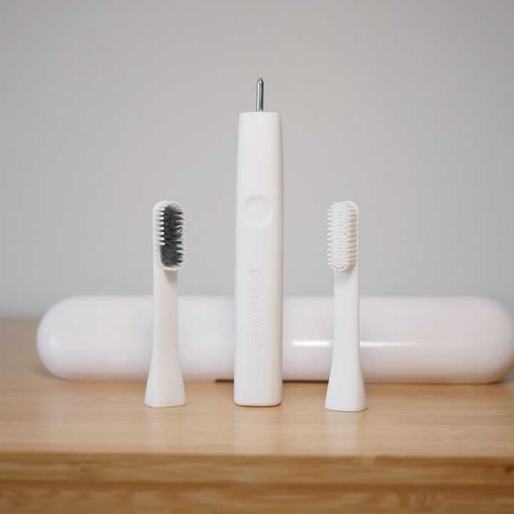 PomaBrush silicone toothbrush on table with brush heads.
