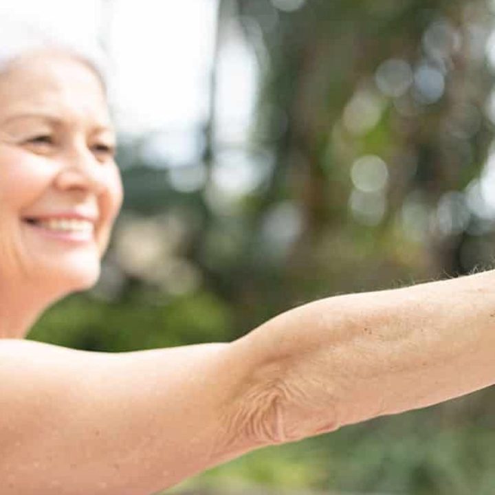 A smiling older woman wearing a goVia device on her wrist while exercising.