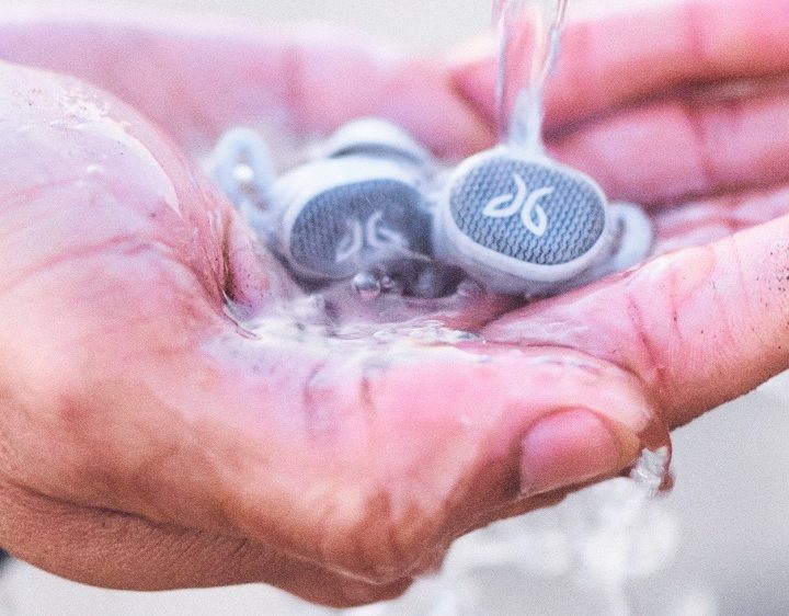 Jaybird Vista 2 earbuds in palm with water pouring.