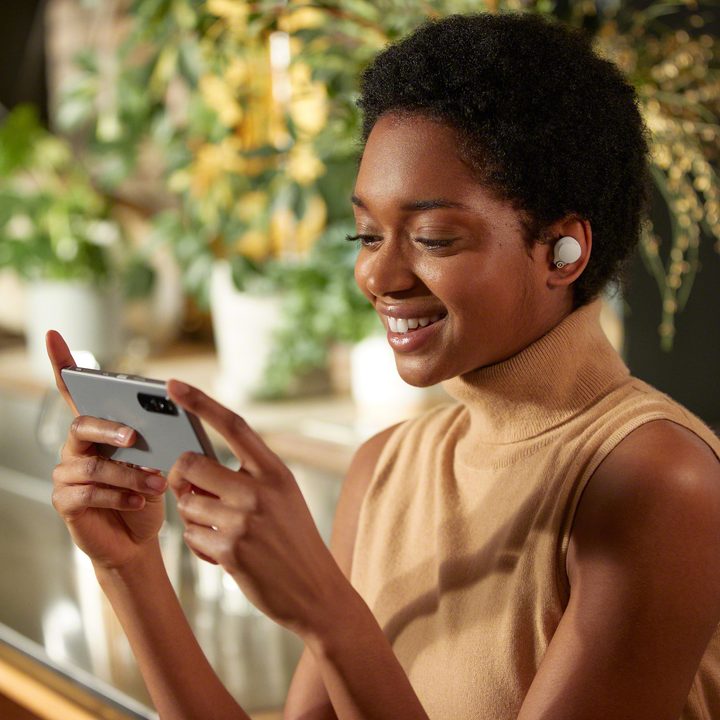 Person wearing the Sony WF-1000XM4 using a phone.