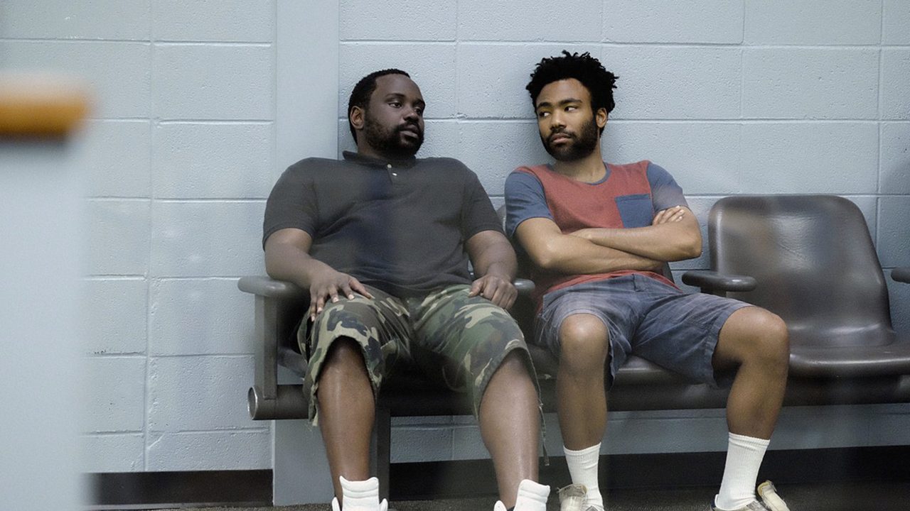 Two guys sitting in waiting area chairs on Atlanta on Hulu.
