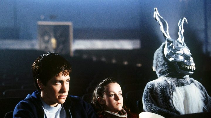 Donnie, Gretchen, and Frank the bunny at an empty cinema looking at the screen in Donnie Darko.
