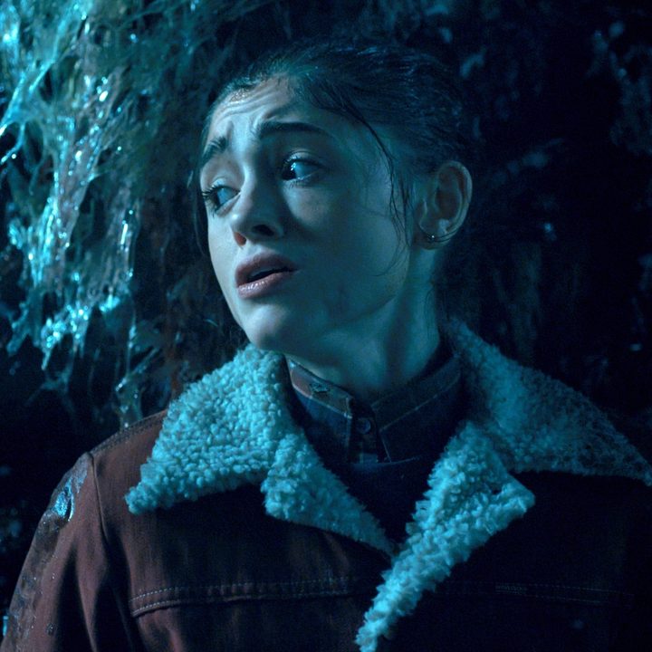 Natalia Dyer hides behind a tree in Stranger Things.