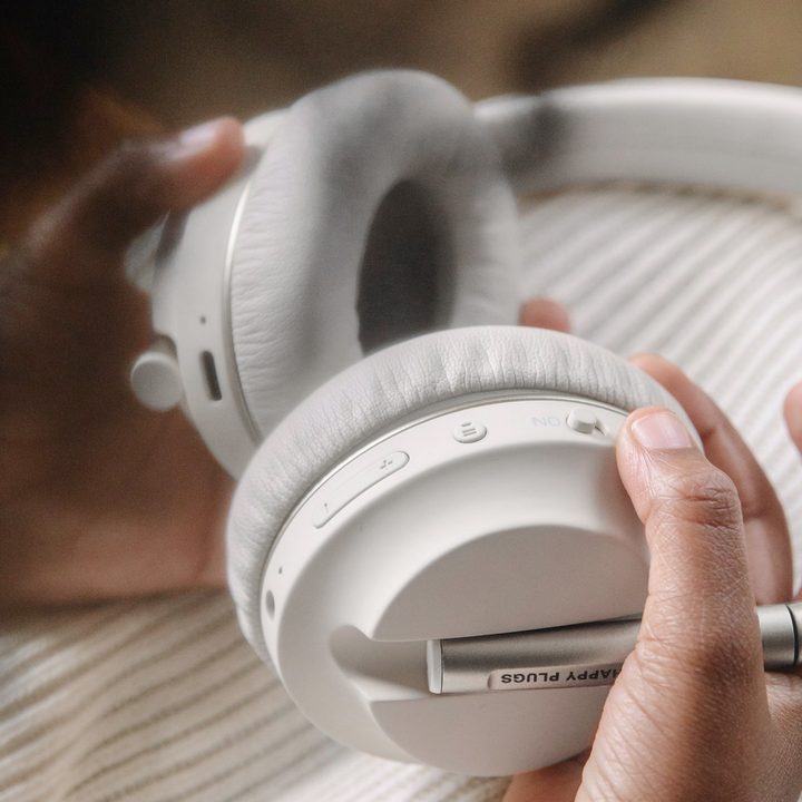 Hands holding Happy Plugs Play headphones.