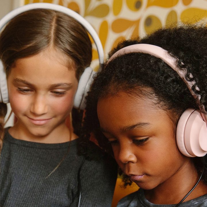 Two girls wearing Happy Plugs Play headphones.
