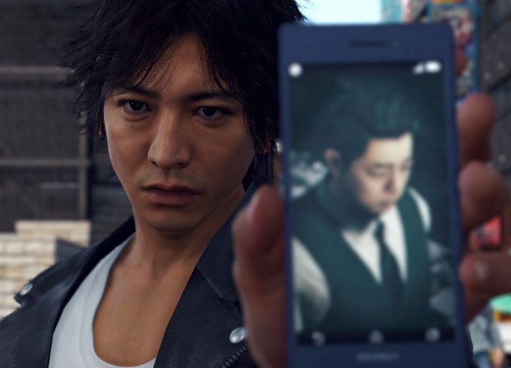 The main character of Lost Judgment holds a phone.