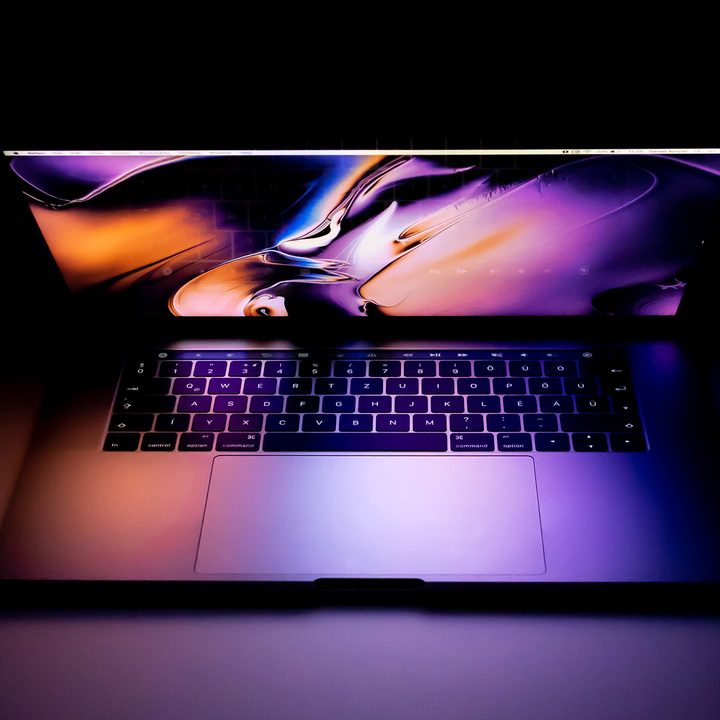 MacBook Pro with screen partially open on a black background.
