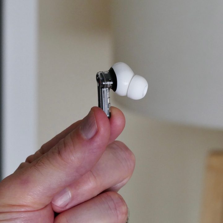 The Nothing Ear 1 held between two fingers.
